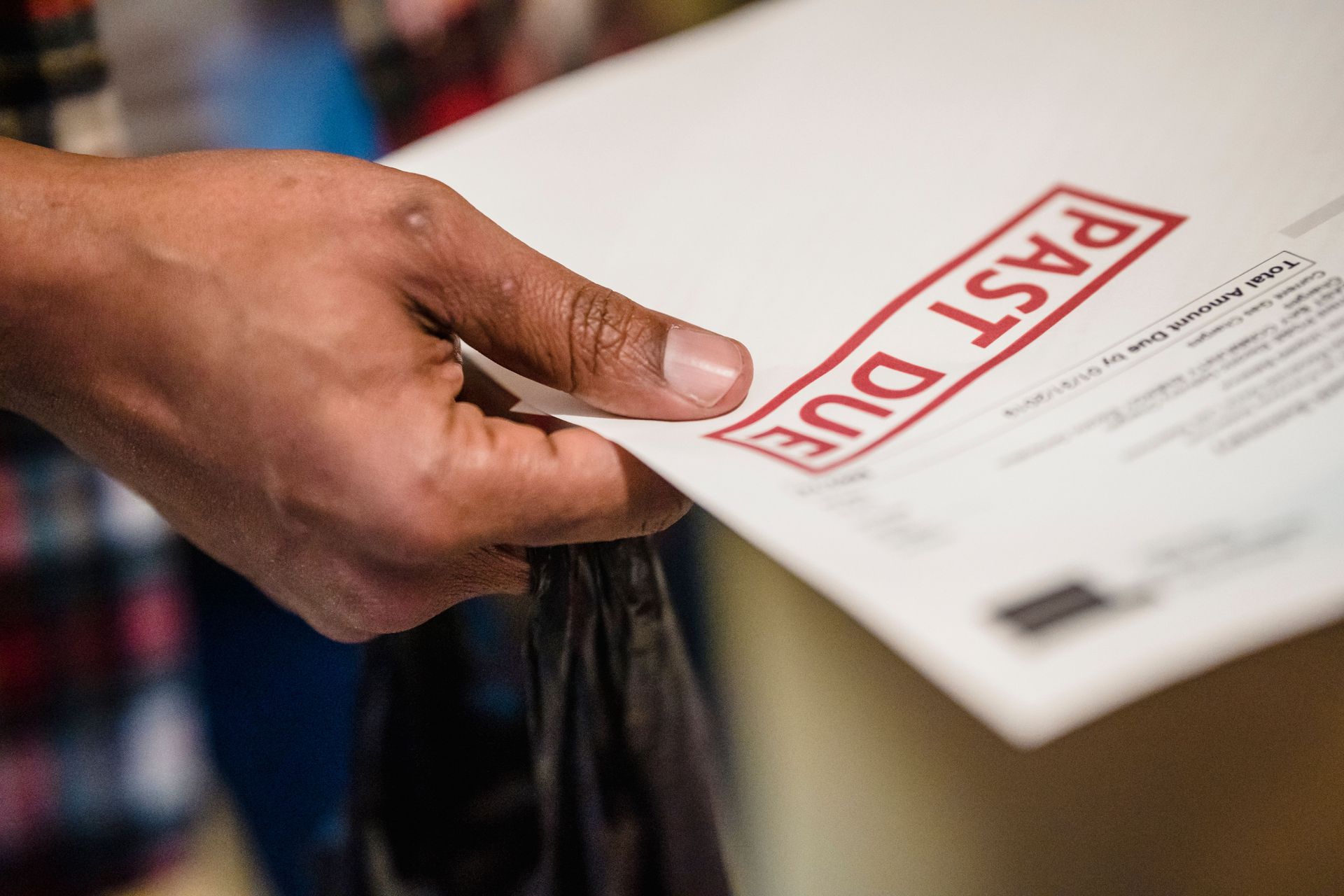 Hand placing a red “PAST DUE” notice on a stack of papers