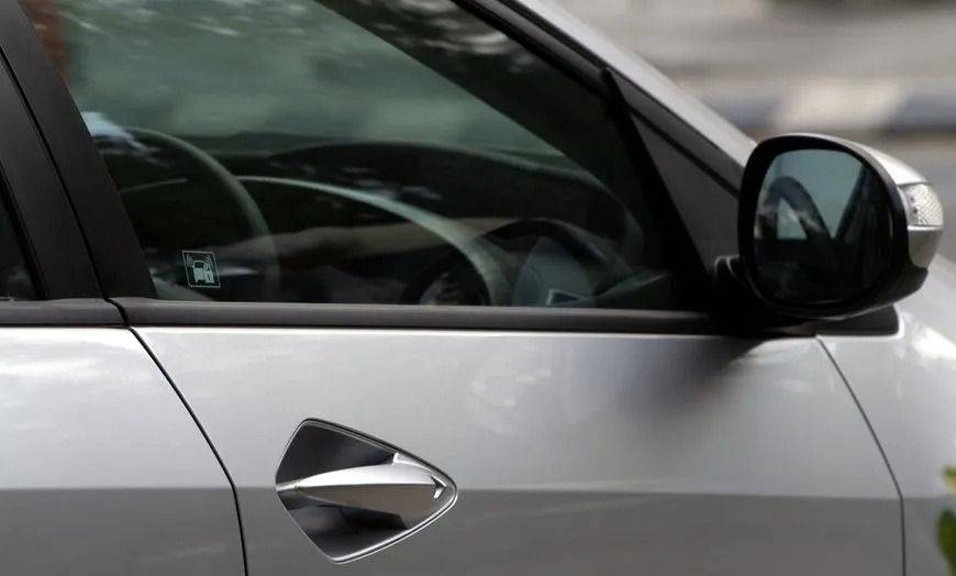 Close-up of a silver car door, window, and side mirror.