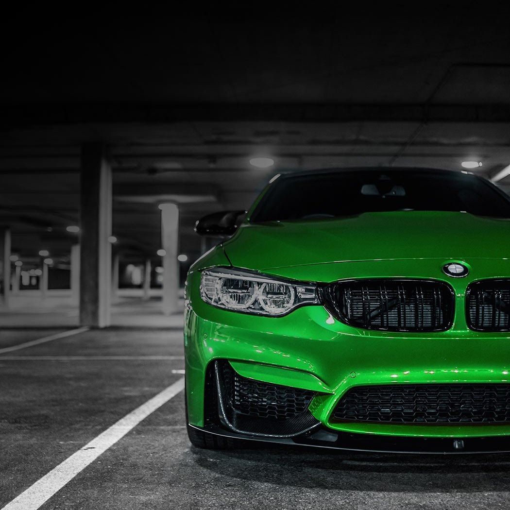 Bright green sports car parked in a dim parking garage, front view