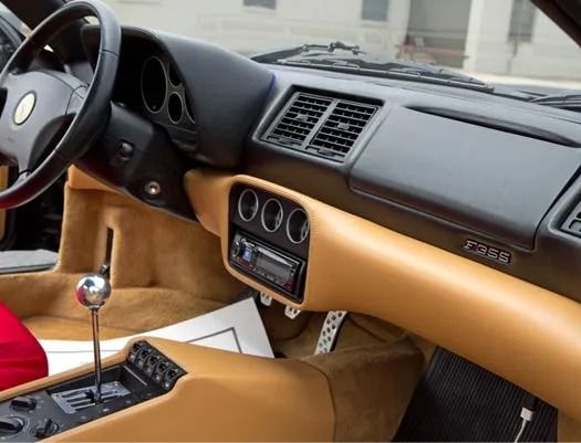 Luxury sports car interior with tan leather dashboard, black steering wheel, and center console.