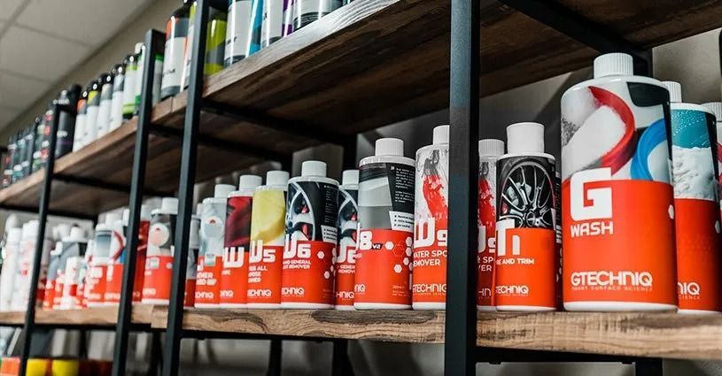 Shelves stocked with orange-and-white Gtechniq car care bottles in a store aisle