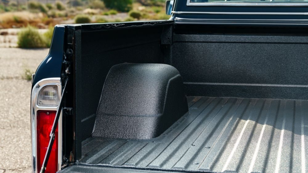 Red pickup truck with open tailgate, carrying lumber, a red toolbox, and a coiled extension cord.