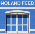 Blue building with white trim; "NOLAND FEED" sign above double doors.