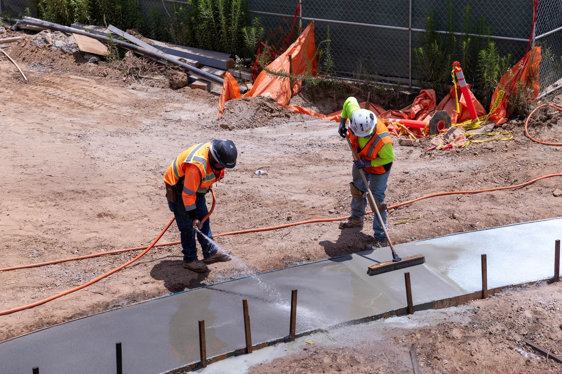 Workers in neon safety vests paving a road at a residential street corner