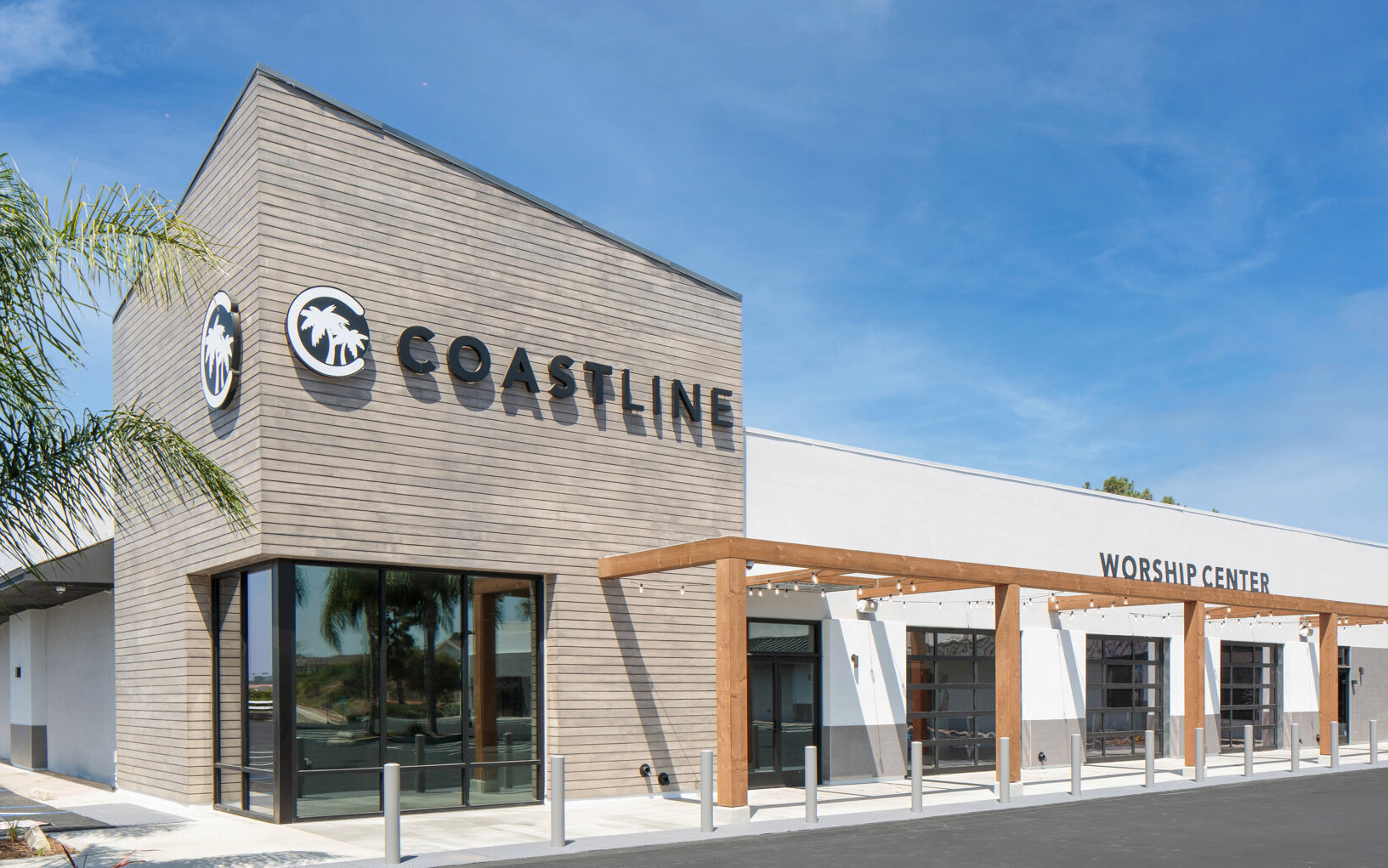 Modern storefront with a tan facade, glass doors, and the word “COASTLINE” on the building.