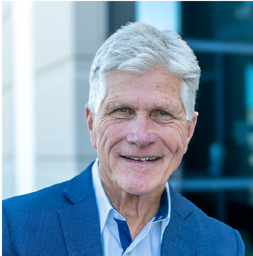 Portrait of a smiling man in a blue blazer against a blurred office background