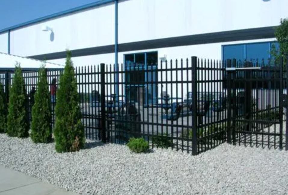 Black metal fence surrounding outdoor seating area, gravel ground, and building exterior.