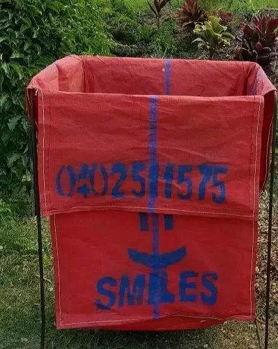 Red Fabric Trash Bin with Blue Text and Smiley Face, Standing Outdoors on Grass — Green Waste in Thuringowa Central, QLD