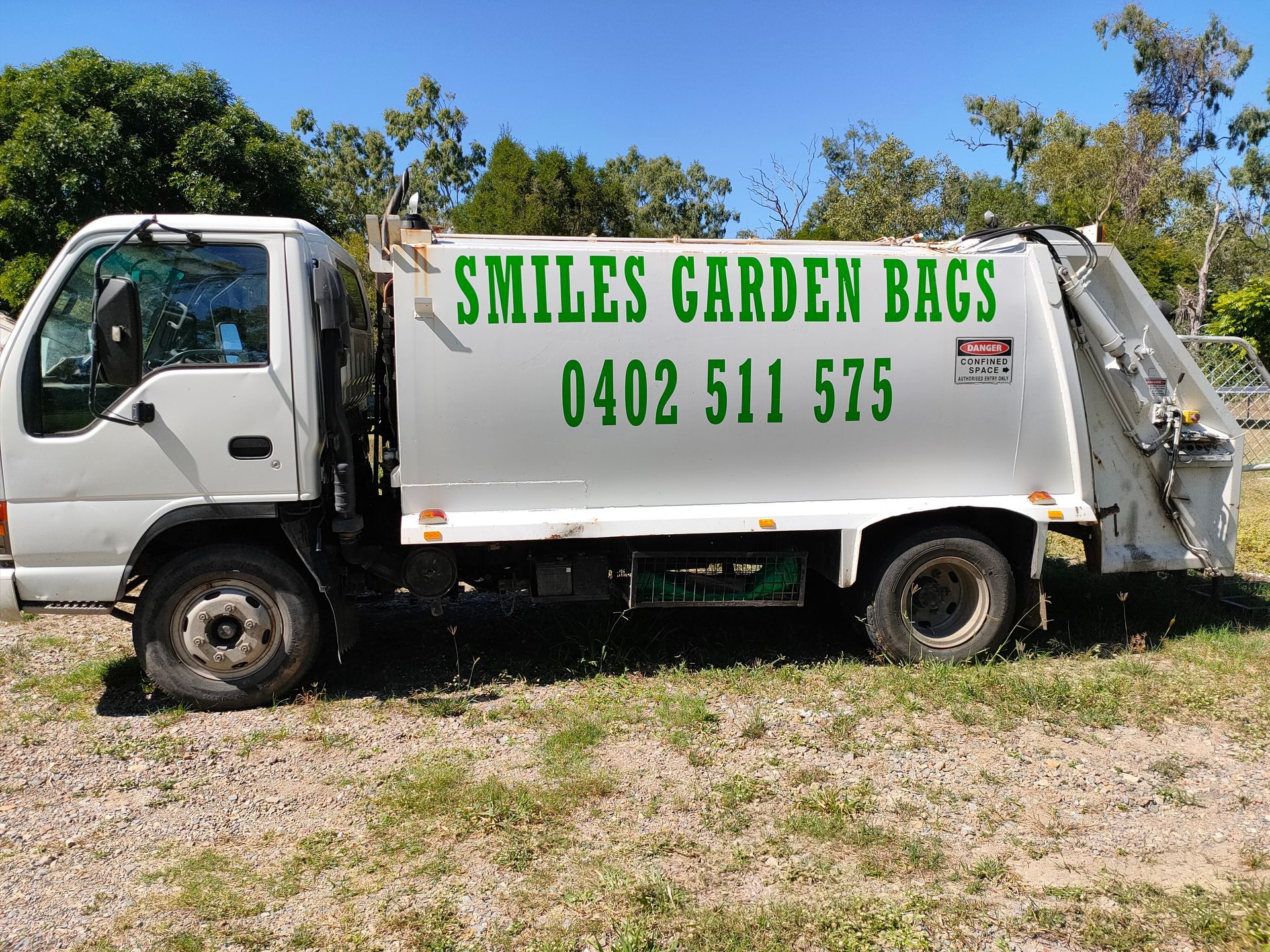 White Garden Waste Truck with Green Smiles Garden Bags Sign Parked on Grass — Green Waste in Thuringowa Central, QLD