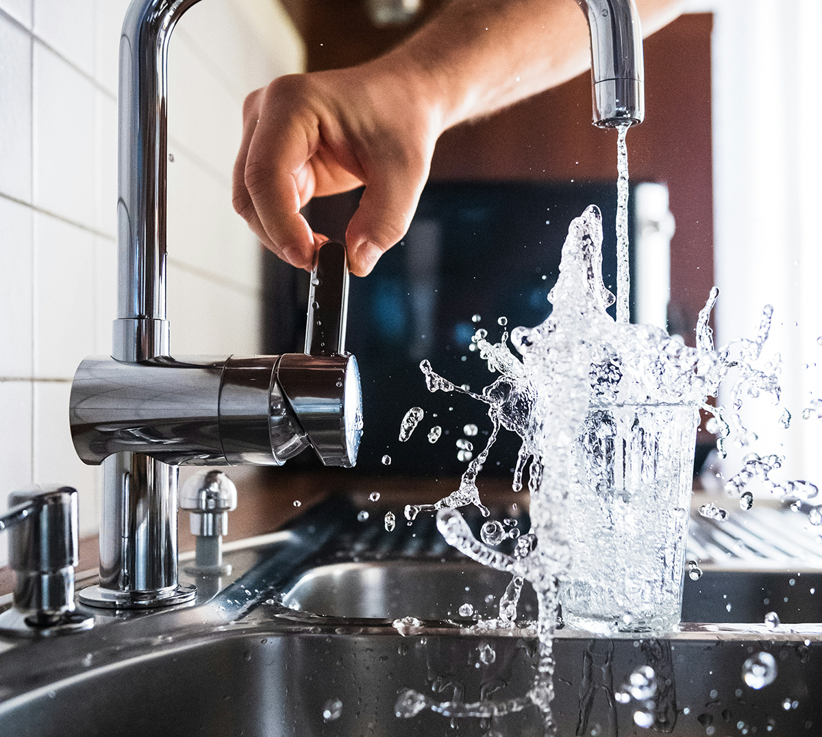 A person is washing their hands in a kitchen sink.