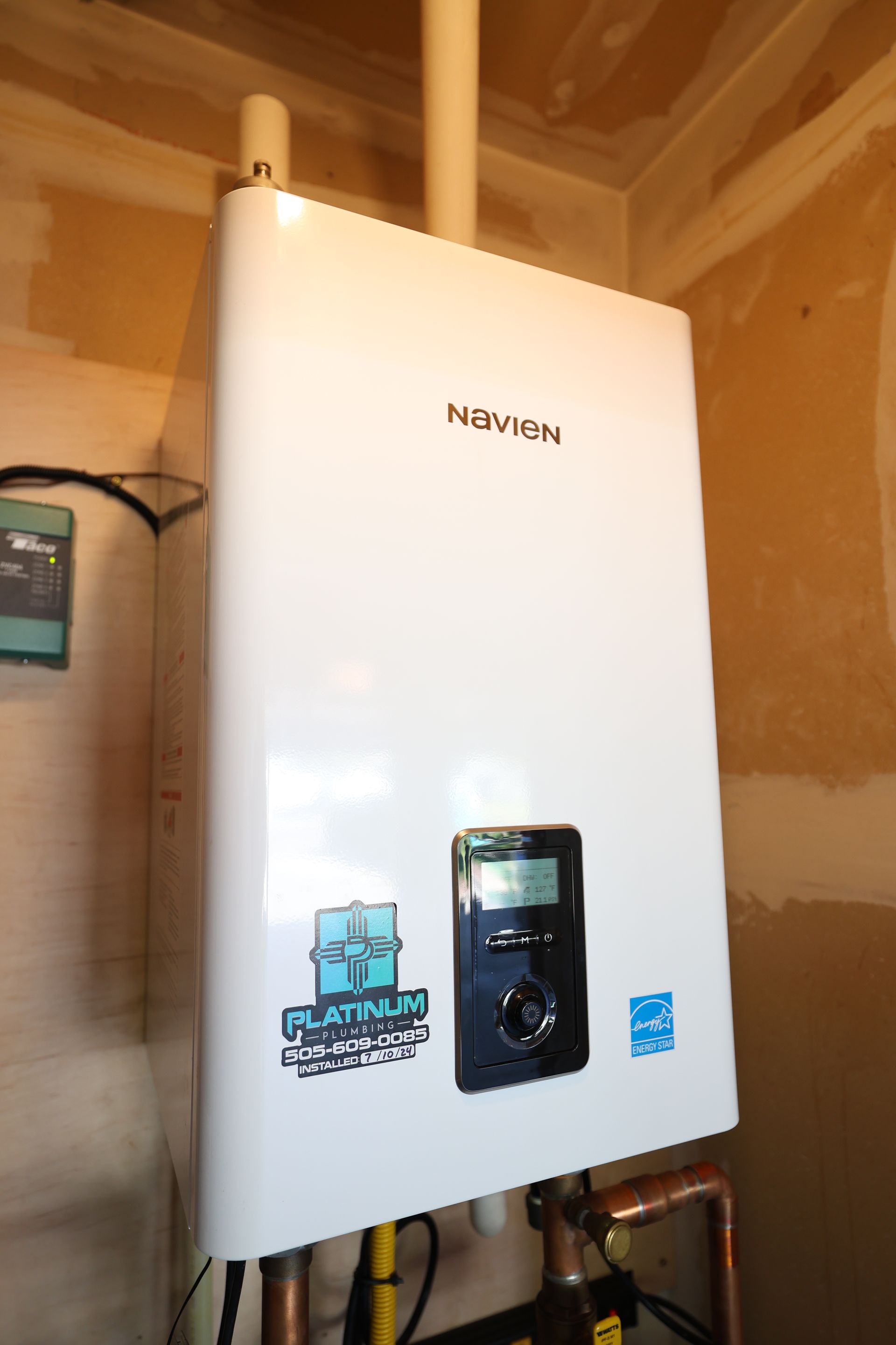 White wall-mounted boiler or water heater with a black control panel in a wooden utility room