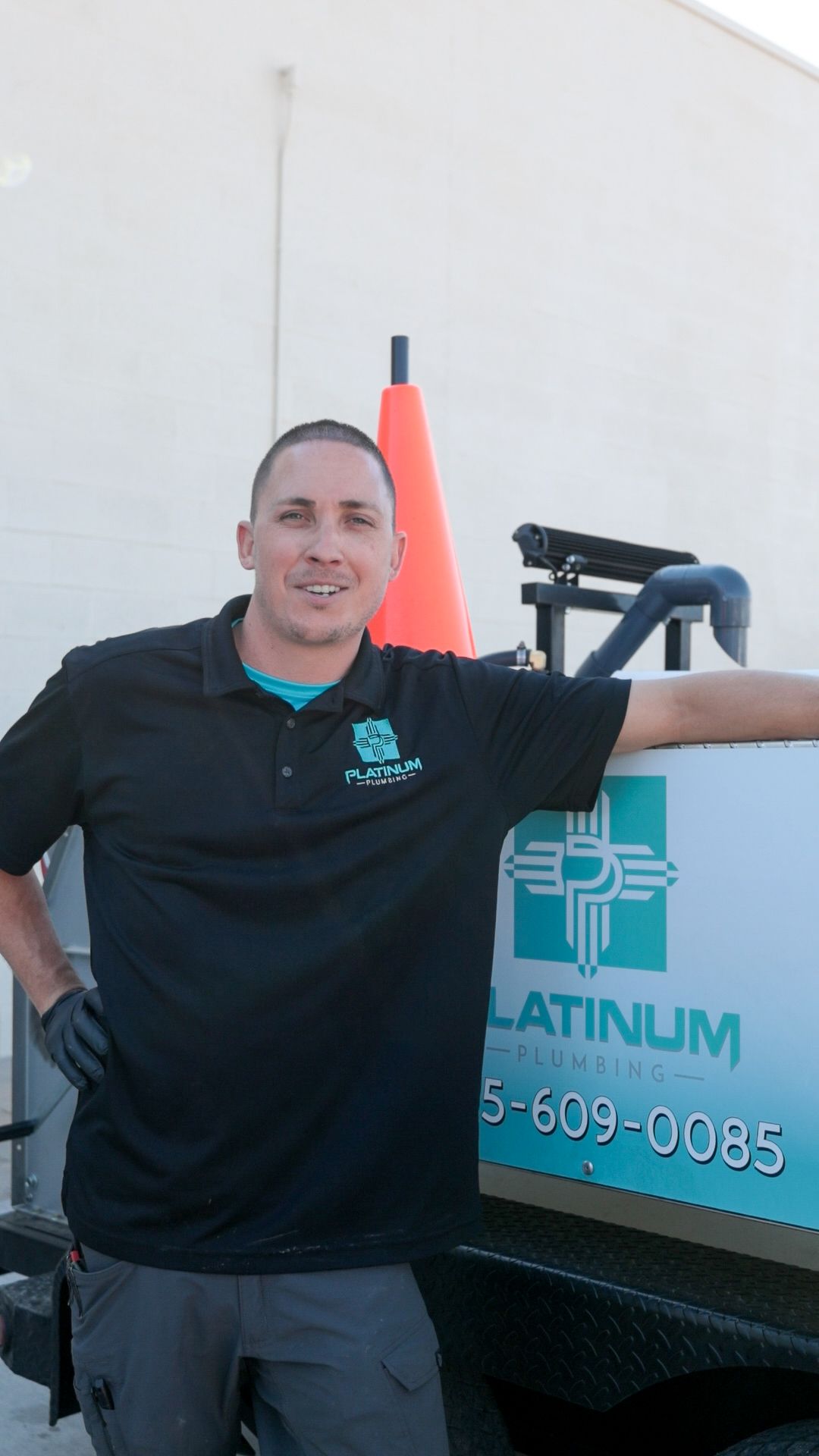 An platinum plumbing employee is standing next to a truck