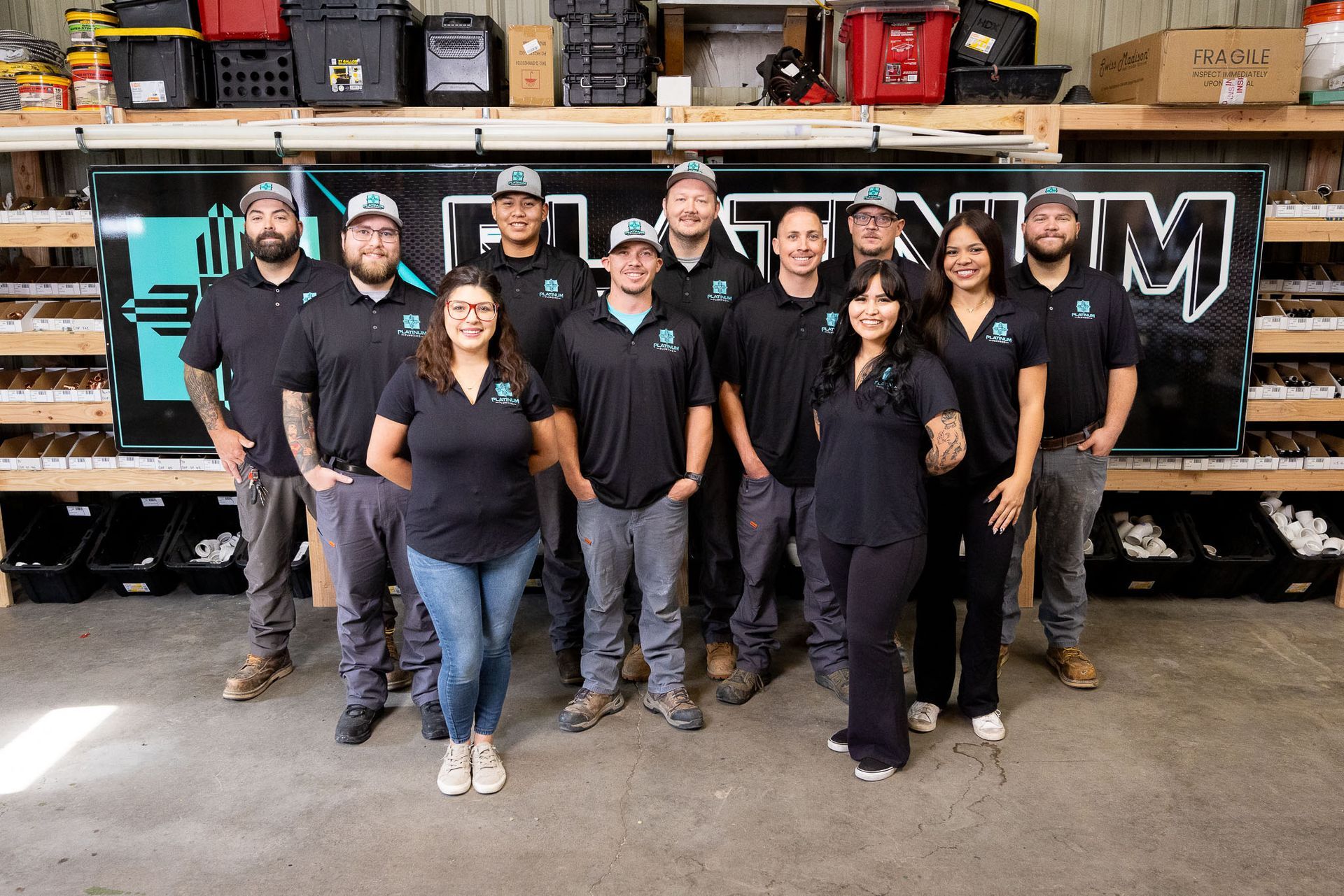A group of people standing in front of a platinum plumbing van.