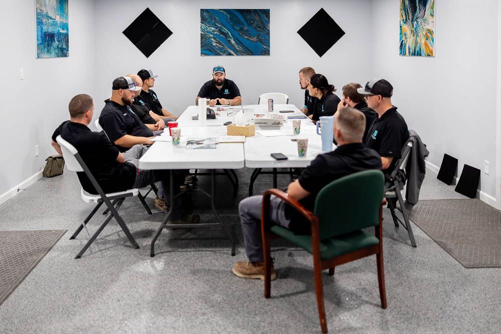 A group of people are sitting around a table with laptops.