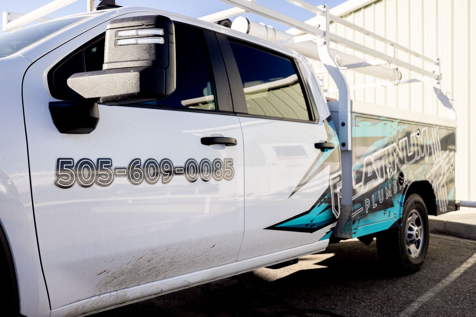 A Platinum Plumbing truck with a ladder rack on top of it is parked in a parking lot.