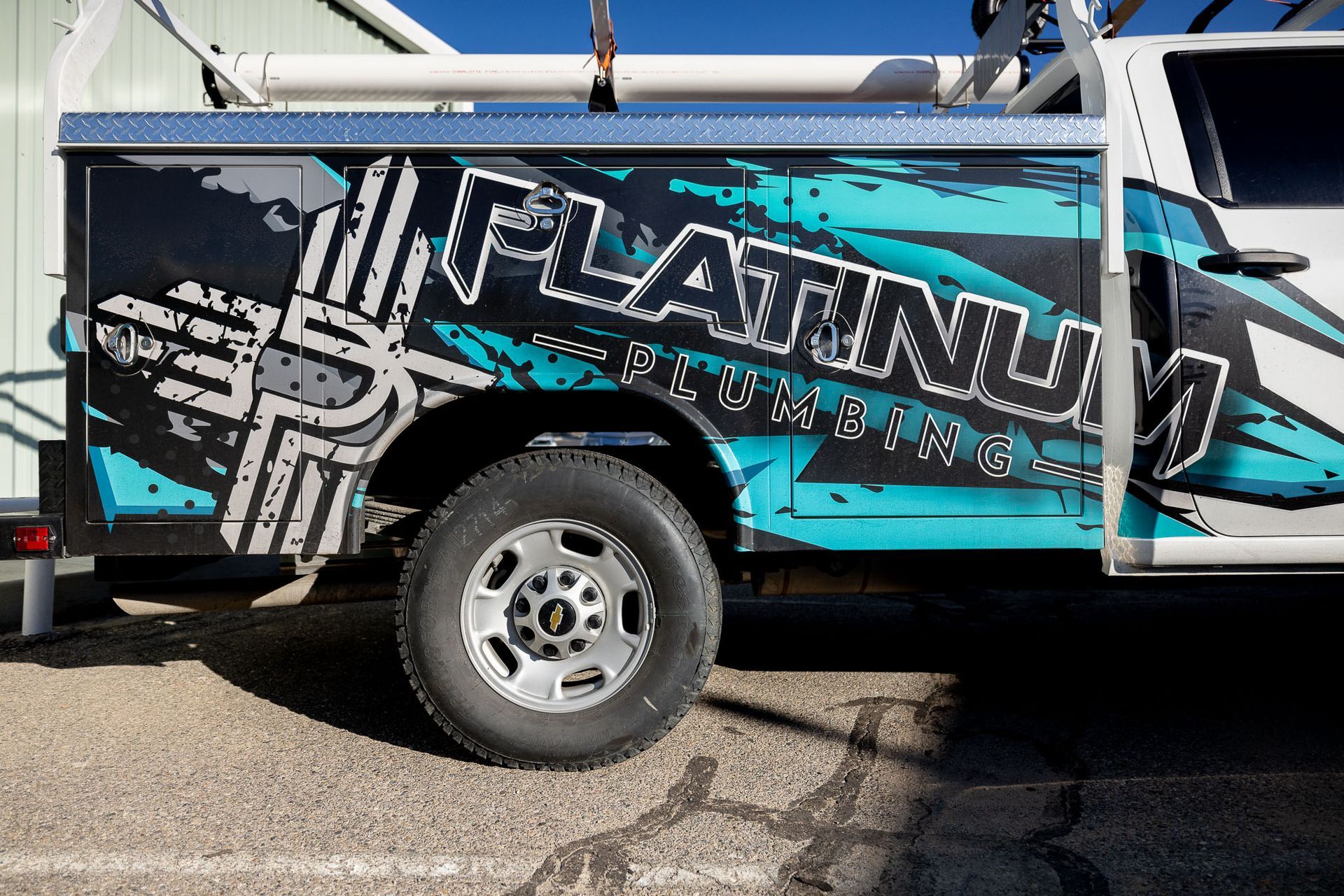 A platinum plumbing truck is parked in a parking lot
