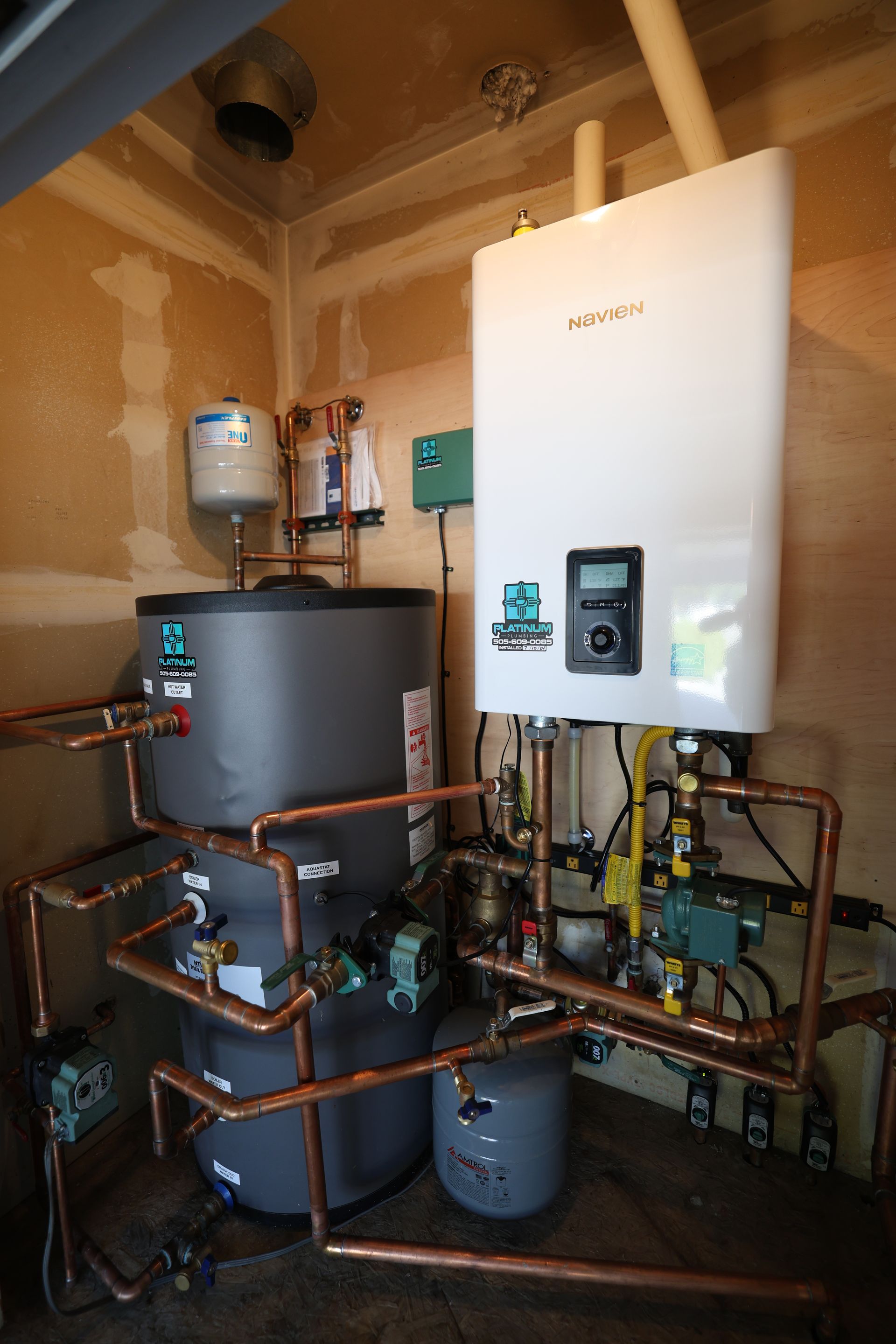 A room with a lot of pipes and a water heater.