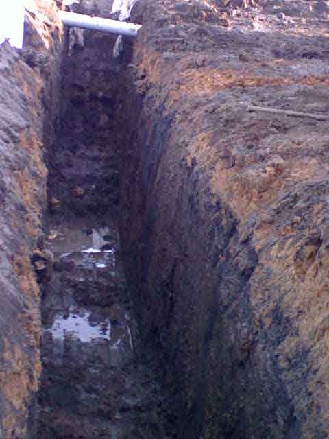 A muddy trench with a pipe in the middle of it.