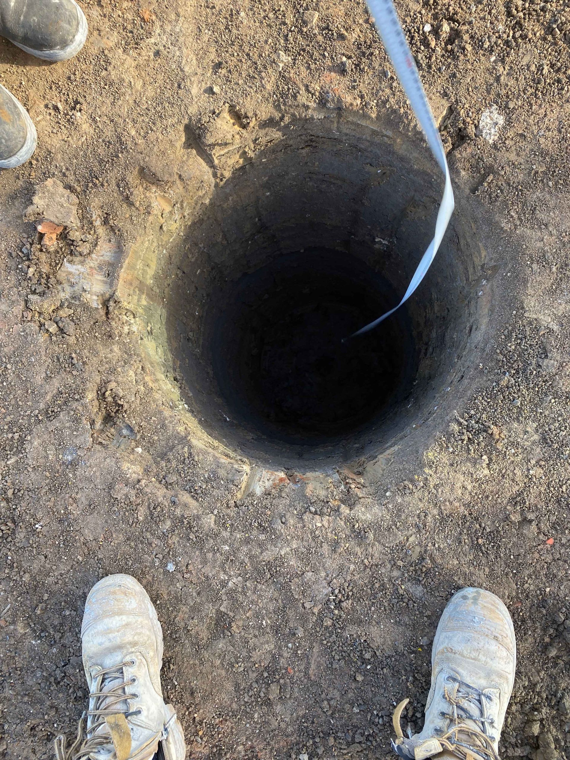 A person is standing next to a hole in the ground.