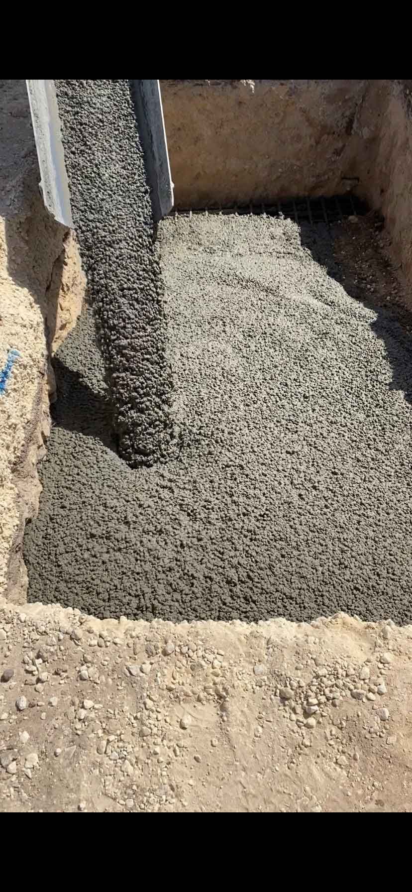 A person is pouring concrete into a hole in the ground.