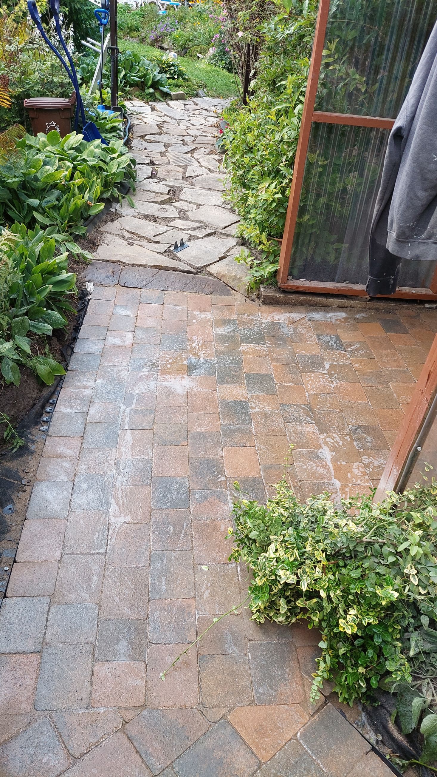 Une allée en briques menant à une serre dans un jardin.