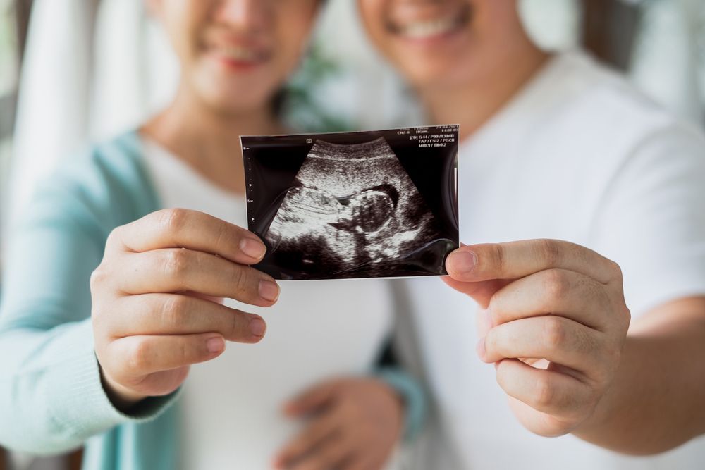 A man and a woman are holding an ultrasound of their baby.