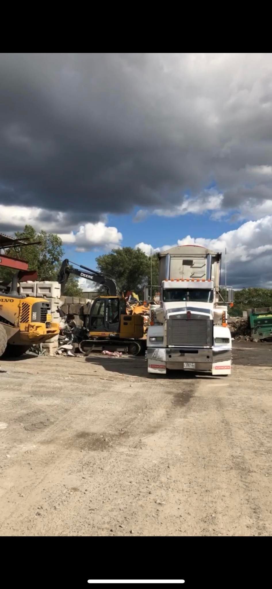 Un semi-remorque blanc est garé sur un terrain avec d'autres camions.
