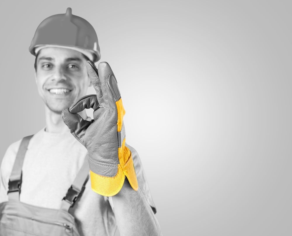 Un ouvrier du bâtiment portant un casque et des gants lève le pouce.