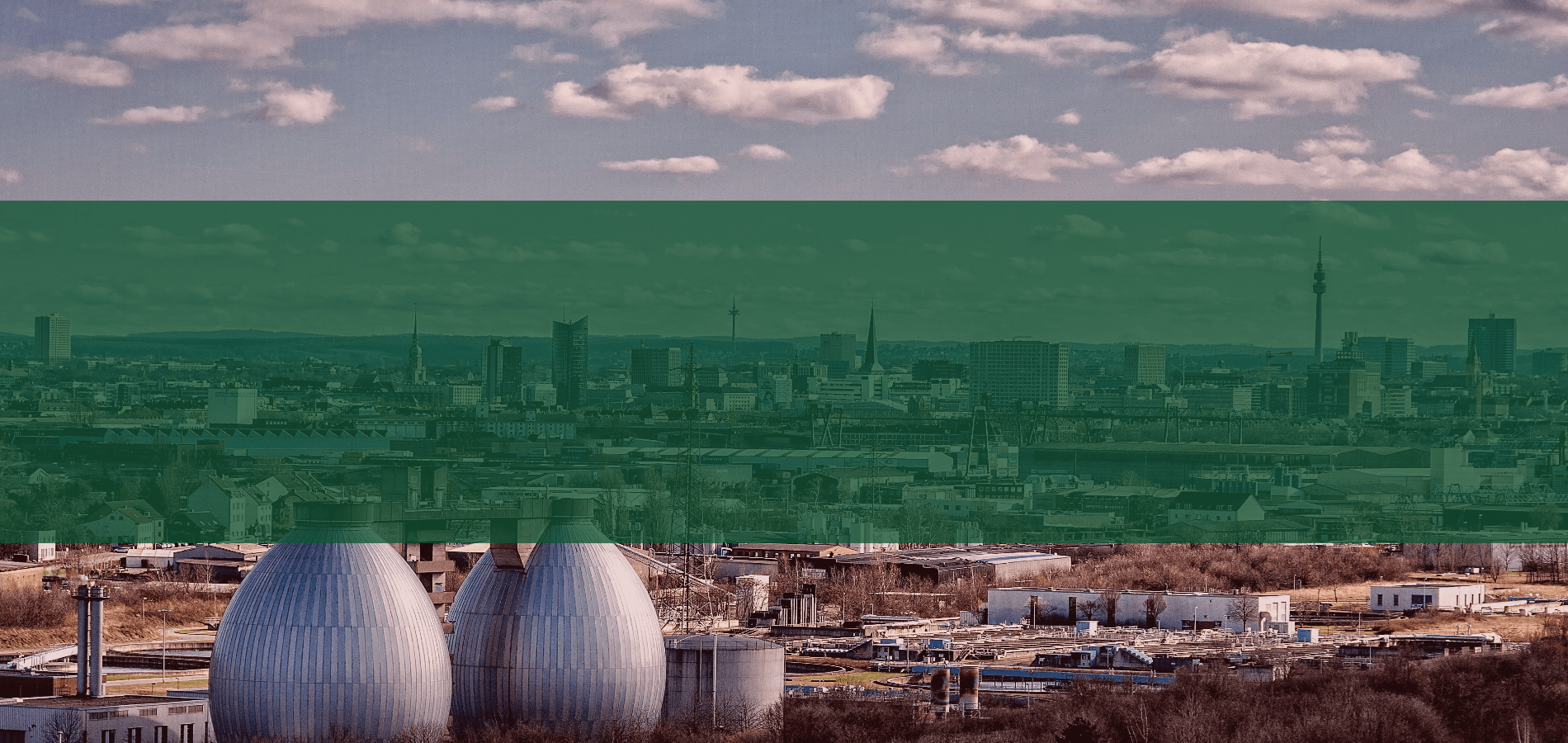Eine Luftaufnahme einer Kläranlage mit einer Stadt im Hintergrund.