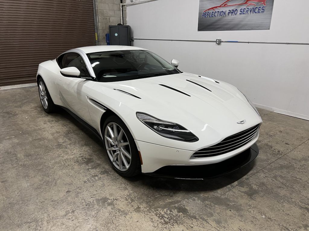 A white aston martin db11 is parked in a garage.
