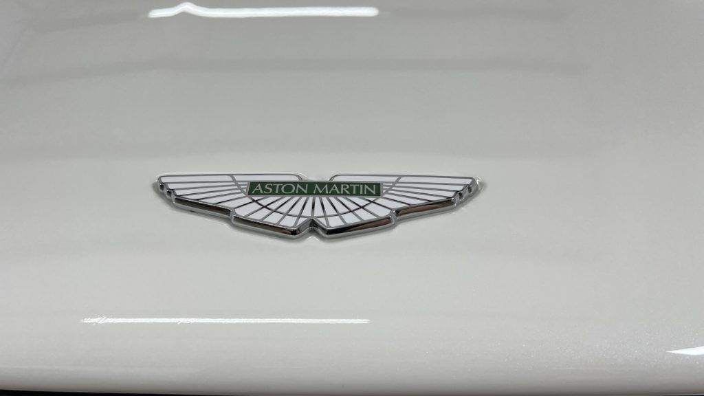 A close up of a white aston martin emblem on the side of a car.
