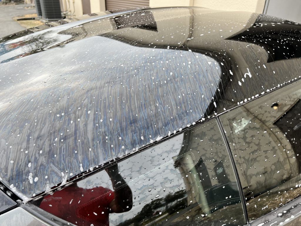 A black car with a reflection of a building in the windshield