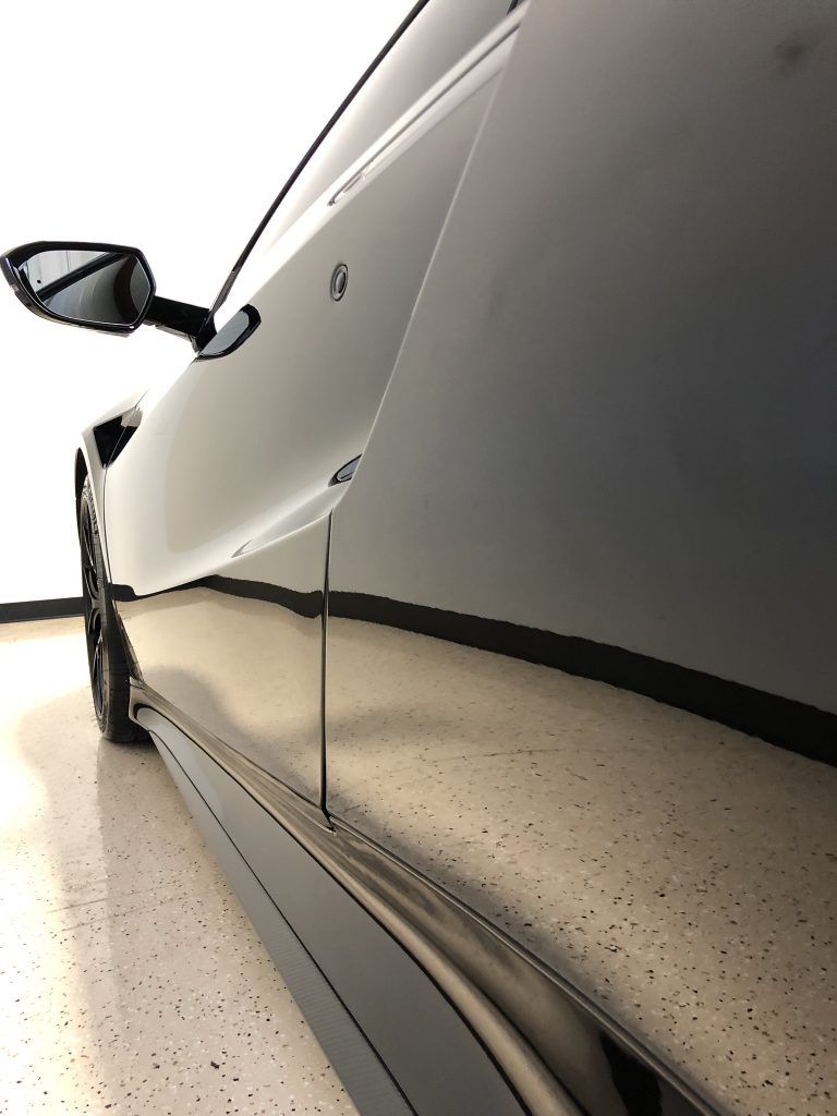 A car is parked in a garage with the door open