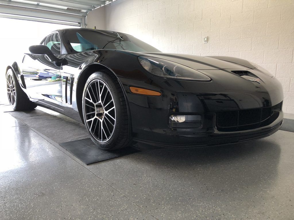 A black sports car is parked in a garage.