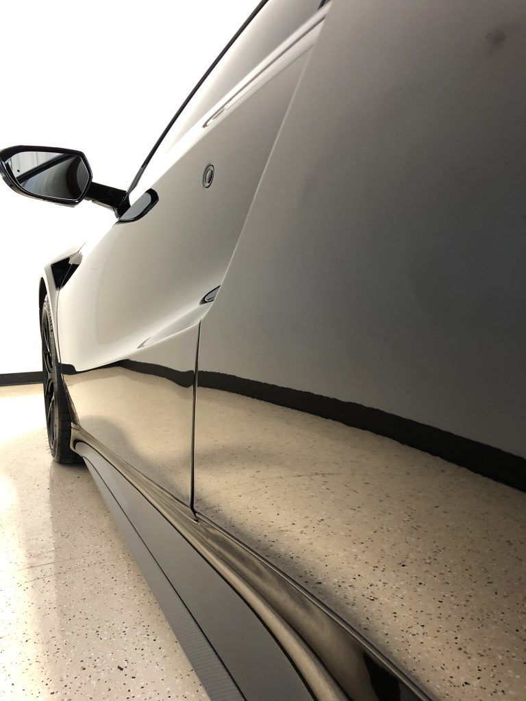 A black sports car is parked in a garage.