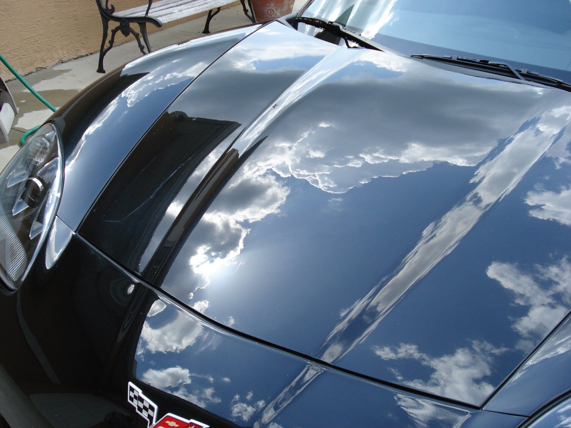 The hood of a black sports car with a corvette logo on it