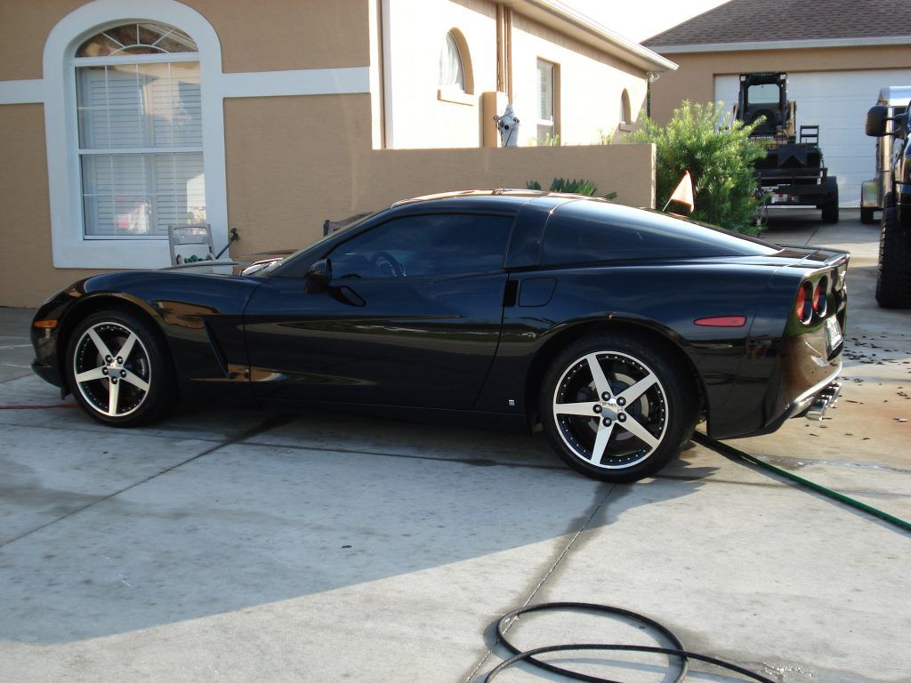 A black sports car is parked in front of a house