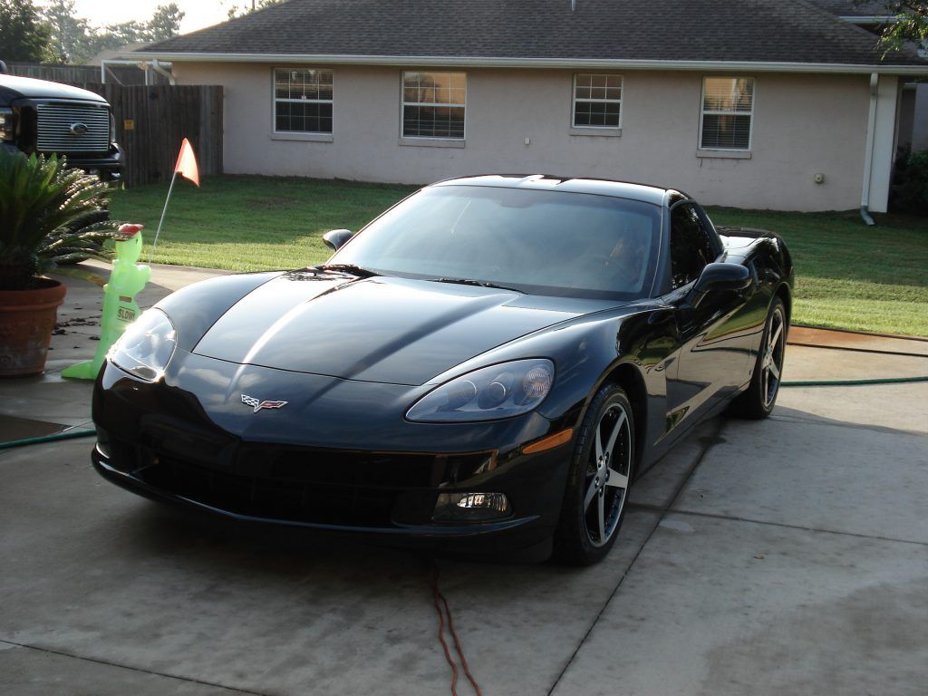 A black sports car is parked in front of a house