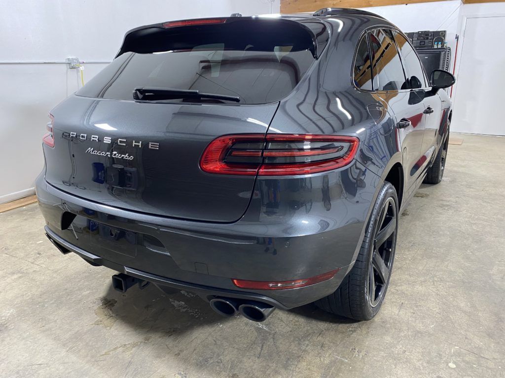 A gray porsche macan is parked in a garage.