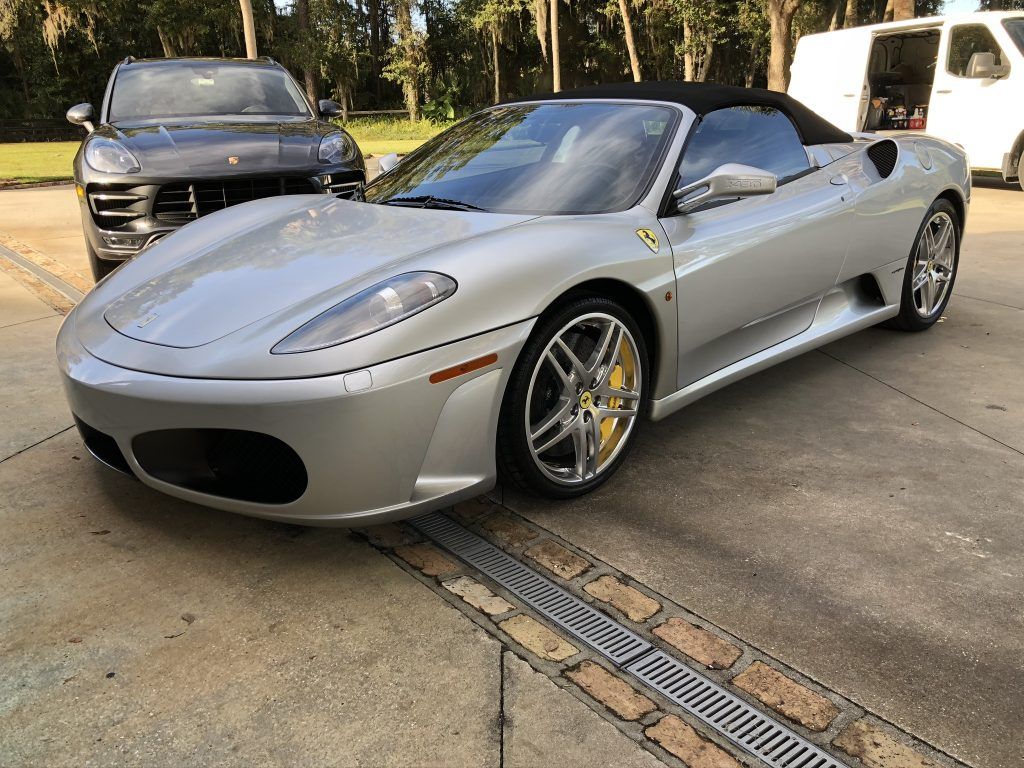 A silver sports car is parked next to a black car in a parking lot.