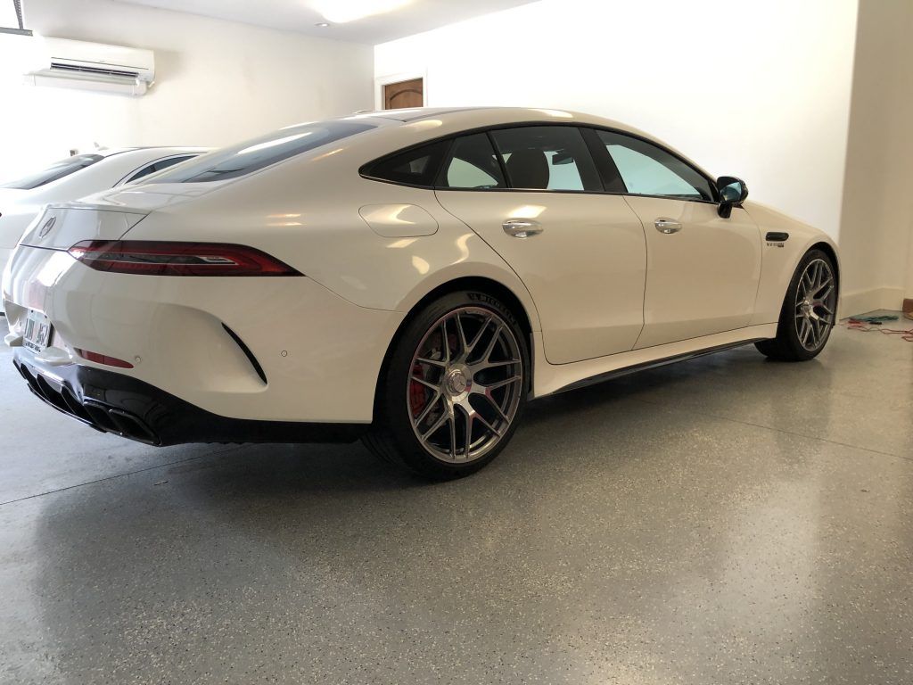 A white sports car is parked in a garage.