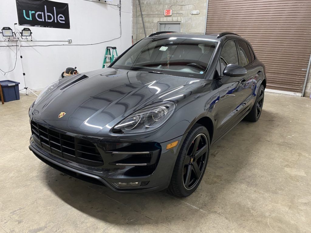 A black porsche macan turbo is parked in a garage.