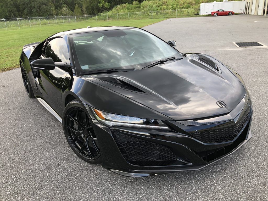 A black sports car is parked in a parking lot.