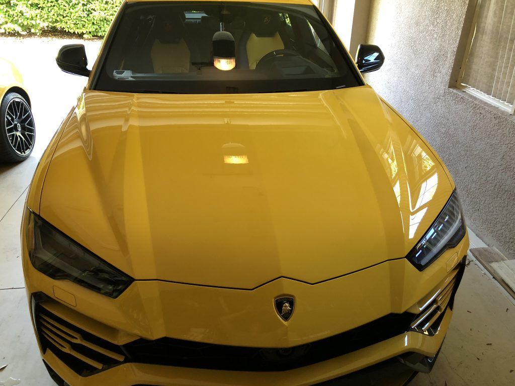 A yellow lamborghini urus is parked in a garage