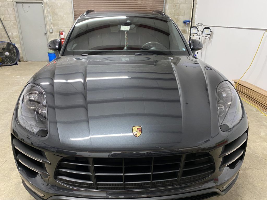 A black porsche macan is parked in a garage.