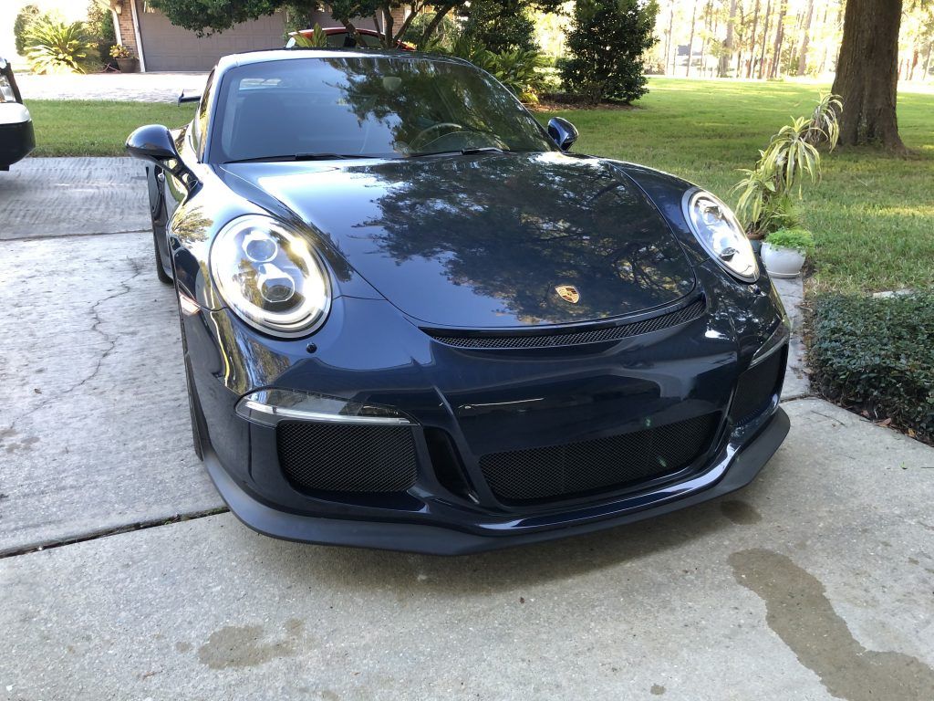 A black porsche 911 gt3 rs is parked in a driveway.