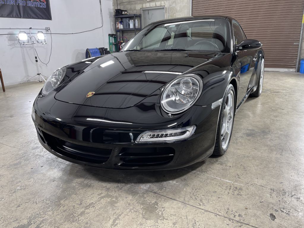 A black porsche 911 is parked in a garage.