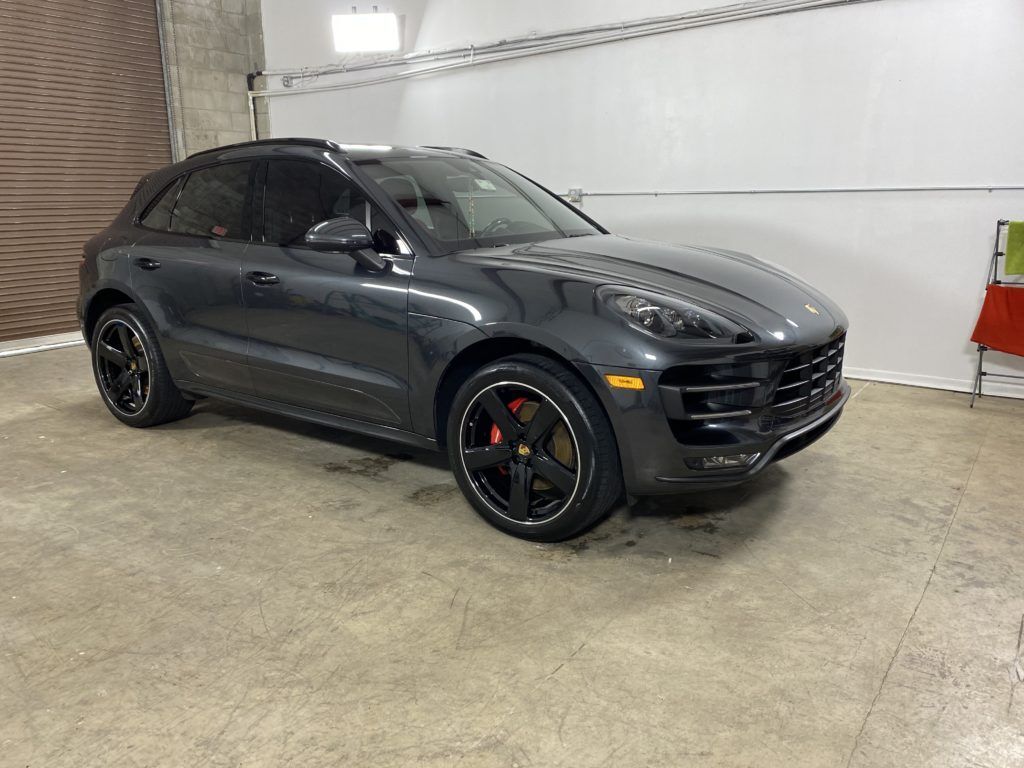 A gray porsche macan turbo is parked in a garage.