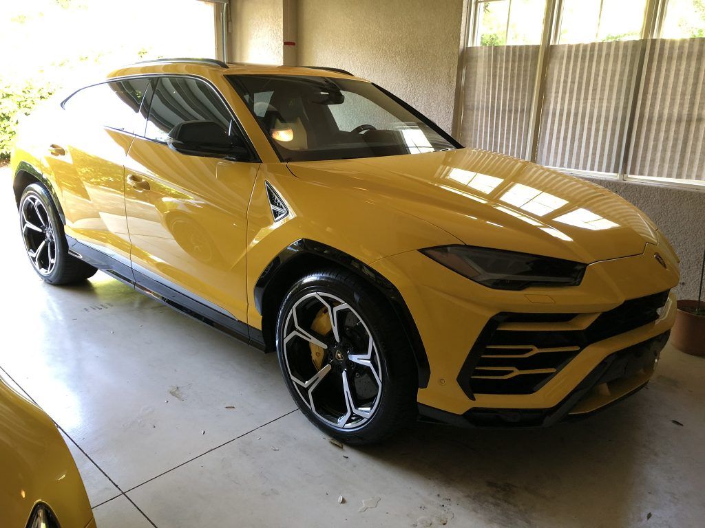 A yellow lamborghini urus is parked in a garage.