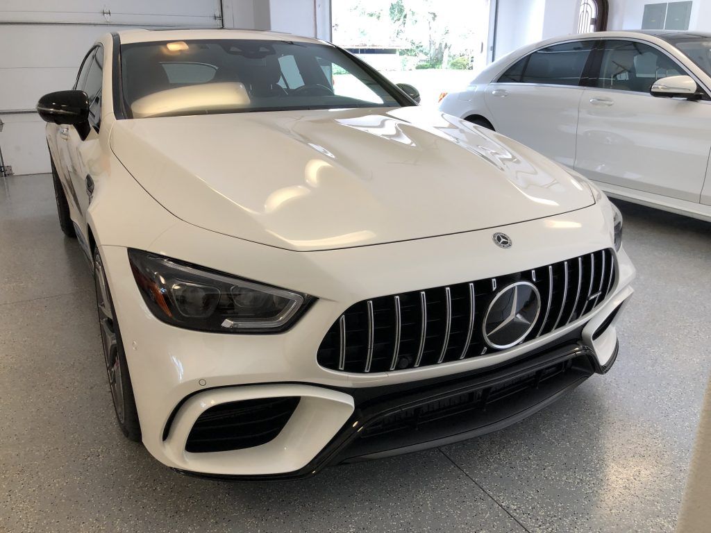 A white mercedes benz is parked in a garage.